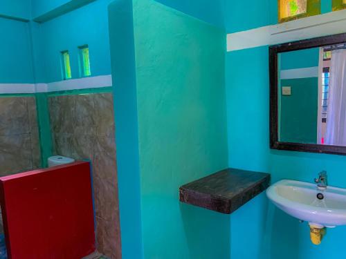 Baño verde con lavabo y espejo en Breeze Hostel en Kuta Lombok