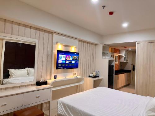 a bedroom with a bed and a flat screen tv at KUMU Lantai 18 Warhol Residence at Louis Kienne Simpang Lima Semarang in Semarang