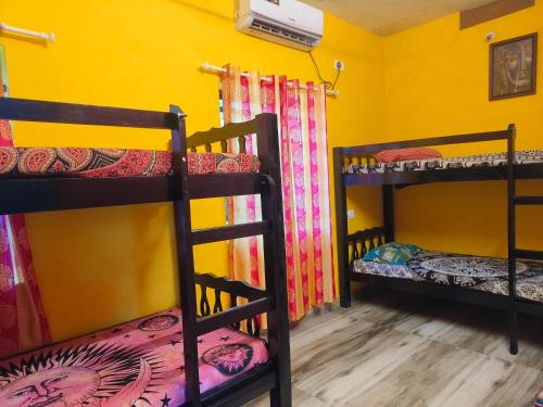 a room with three bunk beds and a yellow wall at Peace and love stay in Alleppey