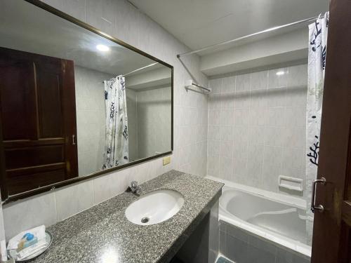 a bathroom with a sink and a mirror and a tub at Silversand Villa Hotel in Jomtien Beach