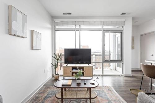 a living room with a tv and a table at CozySuites l Lavish 1BR, Bottleworks Indy #4 in Indianapolis