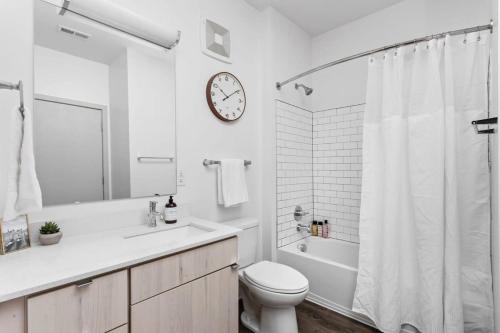 uma casa de banho com WC e um relógio na parede em CozySuites l Dream 1BR, Bottleworks Indy #6 em Indianápolis