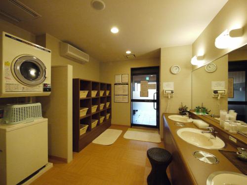 Route Inn Grantia Himi Wakuranoyado في هيمي: حمام مع مغسلتين وغسالة ملابس