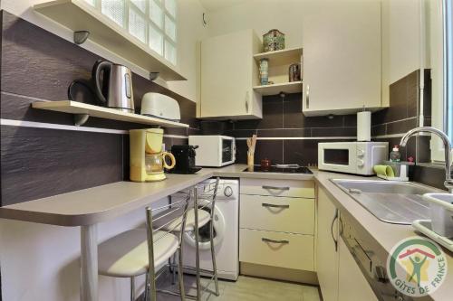 une petite cuisine avec des armoires blanches et un évier dans l'établissement Evasion, à Dinard