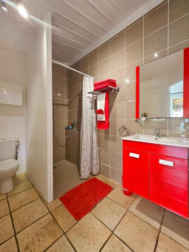 La salle de bains est pourvue d'un lavabo rouge et d'une douche. dans l'établissement L'Eskalya *** avec jacuzzi et piscine partagée, vue océan, à Saint-Joseph