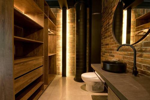 een badkamer met een toilet, een wastafel en een bakstenen muur bij Hotel Meridiano Lofts in Medellín