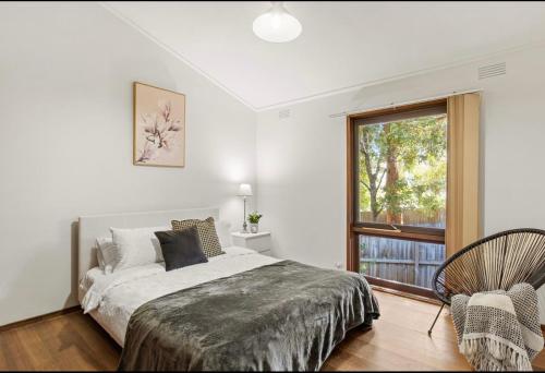 a bedroom with a bed and a window and a chair at Tsapas Homes in Doncaster East