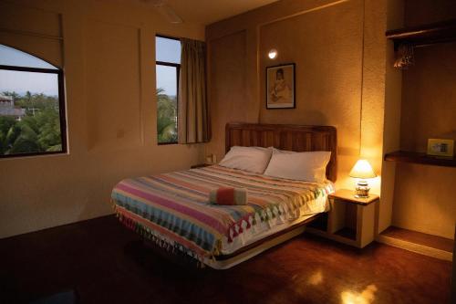 a bedroom with a bed with a lamp and two windows at Cielito Lindo Suites in Puerto Escondido