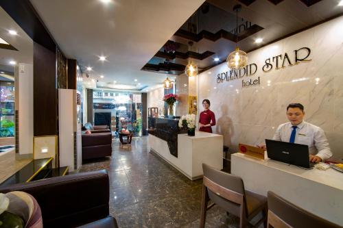 a man sitting at a counter with a laptop in a restaurant at Splendid Holiday Hotel Spa in Hanoi