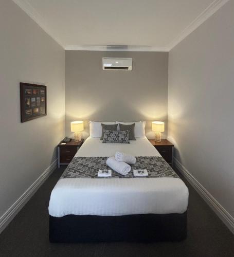a hotel room with a bed with two towels on it at Silver Haven Motor Inn in Broken Hill