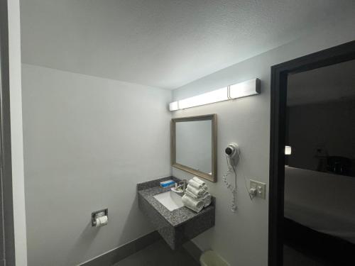 La salle de bains est pourvue d'un lavabo et d'un miroir. dans l'établissement Days Inn by Wyndham Shawnee, à Shawnee