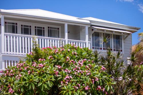 ein weißes Haus mit rosa Blumen davor in der Unterkunft Seaside apartment, 100m to beach in Narrabeen