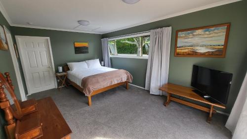 a bedroom with a bed and a flat screen tv at Dewdrop Cottage in Hastings