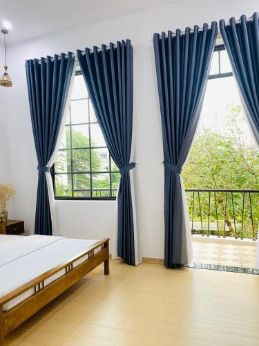 a bedroom with blue curtains and a large window at Romo Homestay in Quang Ngai