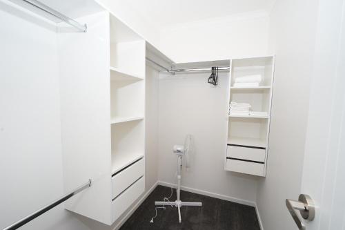a bathroom with white walls and white shelves at Charming 4bds House with 3 bathrooms Brand New in Hamilton
