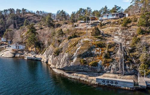 a house on a hill next to a body of water at Lovely Home In Helgeroa With Harbor View in Helgeroa