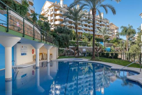 uma piscina em frente a um edifício com palmeiras em Cozy 2 BDRM Apt w Sea Views Next to Puerto Banús em Marbella