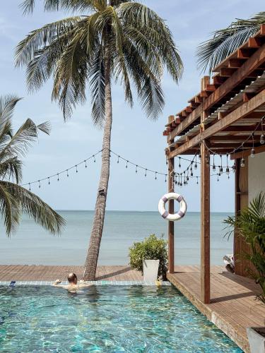 a person in a swimming pool next to a beach at Tango Luxe Beach Villa, Koh Samui in Choeng Mon Beach
