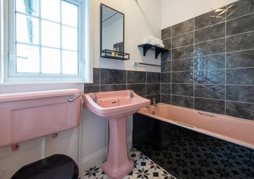 y baño con lavabo rosa y bañera. en Aberhiriaeth Hall en Cemmaes