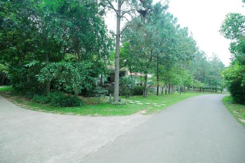 a road with trees and a house in the distance at Villa Owner tại khu nghỉ dưỡng sinh thái Đại Lải Resort in Ngọc Quang