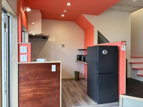 尾道市にあるEast Villa Shimanami Mukaishima seafrontのオレンジ色の天井のキッチン(黒い冷蔵庫付)
