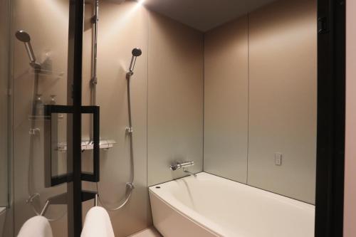 a bathroom with a tub and a shower with a mirror at NOHGA HOTEL UENO TOKYO in Tokyo