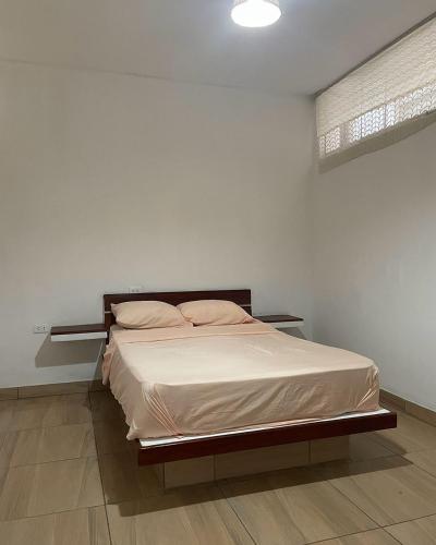 a bed in a bedroom with a white wall at Olas inn in Asia