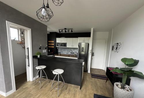 a kitchen with a counter and stools in a room at Saint Sebastian Flat 704 - Com Hidro! até 4 pessoas, Duplex, no centro in Jaraguá do Sul