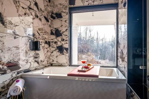 ein Bad mit einer Badewanne und einem Fenster in der Unterkunft Nazm Villa in Gulmarg