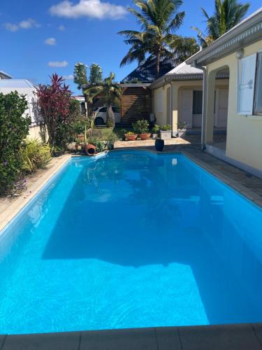 a large blue swimming pool in front of a house at case creole in Saint-Benoît