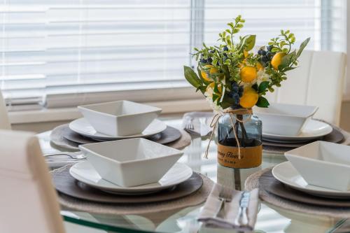 a table with plates and bowls and a vase with flowers at La Maison in Vancouver
