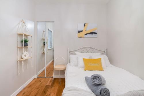 a white bedroom with a bed with a yellow pillow at La Maison in Vancouver