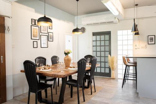 comedor con mesa de madera y sillas negras en The Golden Room - Suvarnabhumi, en Ban Khlong Pha Ong