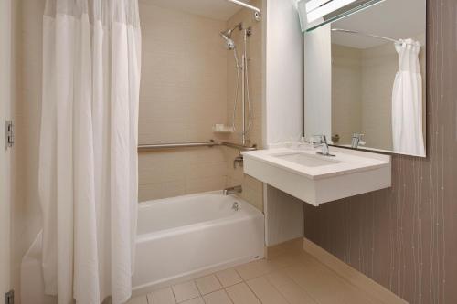 a white bathroom with a sink and a tub and a shower at Courtyard Austin-University Area in Austin