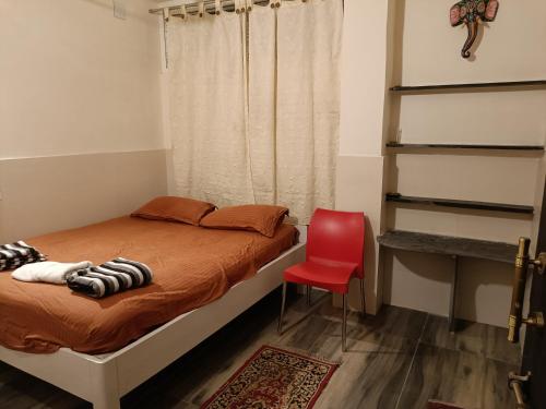 - une chambre avec un lit et une chaise rouge dans l'établissement NIRMAN HOMESTAY 5 minutes walk to beach, à Purî