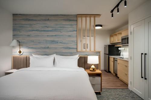 a bedroom with a large white bed and a kitchen at TownePlace Suites by Marriott Geneva at SPIRE Academy in Geneva