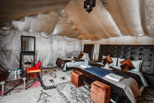 a room with a tent with two beds and a chair at Family Luxury Glamping in Merzouga