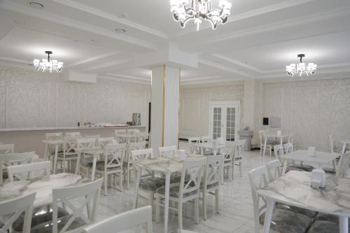 una sala da pranzo con tavoli bianchi e sedie bianche di STATUS HOTEL a Karshi