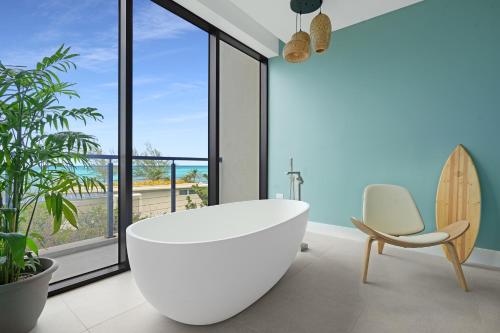 a bathroom with a white tub and a chair and a surfboard at VIDA Cayman in West Bay