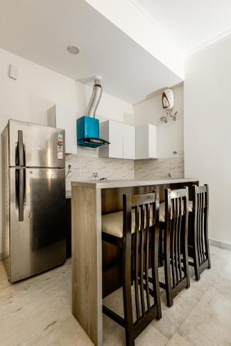 a kitchen with a refrigerator and a bar with chairs at Lime Tree Hotel - Golf Course Road, Sector-43, Gurugram in Gurgaon