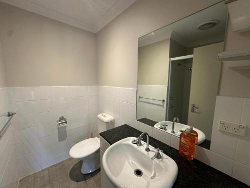 a bathroom with a sink and a toilet and a mirror at Elegant 2 Bedroom home close to city buz Bridge RD 2 E-Bikes Included in Sydney