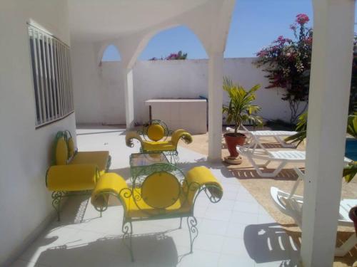 3 gelbe Stühle und ein Tisch auf einer Terrasse in der Unterkunft Keur Fatou in Ngaparou