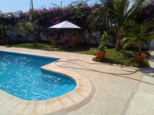 ein Pool mit Sonnenschirm neben einem Hof in der Unterkunft Keur Fatou in Ngaparou