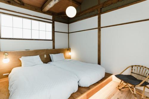 a bedroom with two beds and a chair at 6ishiki in Kameoka