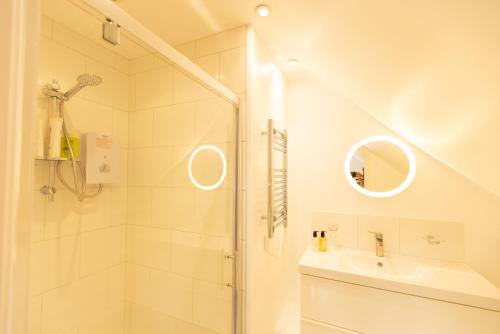 La salle de bains blanche est pourvue d'une douche et d'un lavabo. dans l'établissement 'Lady Hall' Guest House, à Trotterscliffe