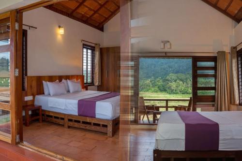 a bedroom with two beds and a large window at HighFields Coorg in Virajpet