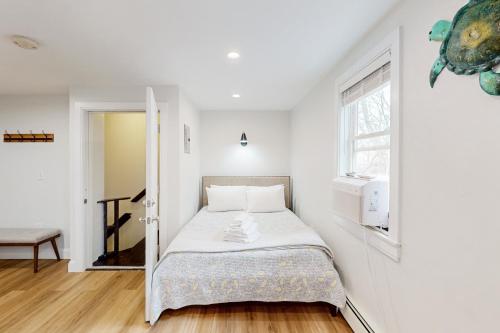 a bed in a white room with a window at Blooming Sunshine - Unit 2 in Falmouth