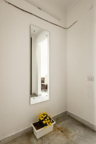 a mirror in a white wall with flowers in a basket at Lime Tree Hotel - Golf Course Road, Sector-43, Gurugram in Gurgaon
