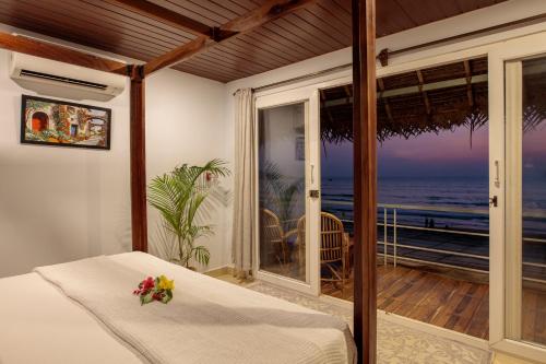a bedroom with a bed and a view of the ocean at Agonda Cottages in Agonda