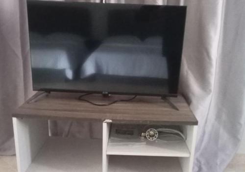 a television sitting on a wooden stand with a table at Adamia Roomstay in Dungun 01 in Dungun